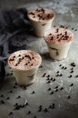 tiramisu in a glass on a gray background with coffee beans