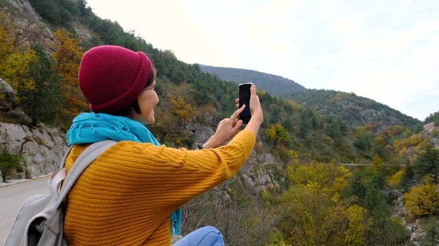 Woman with Backpack Using Smartphone, Hiking In The Mountains And make photo On Smartphone. Solo female hiker using smart phone. Female hiker takes smart phone pic of mountains
