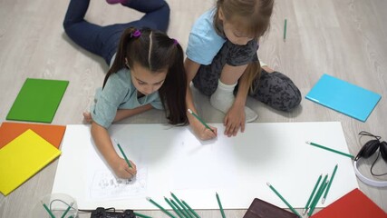 family, leisure and childhood concept - happy sisters lying on floor and drawing and doing homework at home