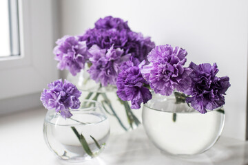 Fototapeta na wymiar Bridal bouquet of lilac carnations in a round glass vase