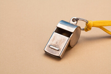 Vintage silver whistle on soft brown paper background. Referee trainer sport competition sound...