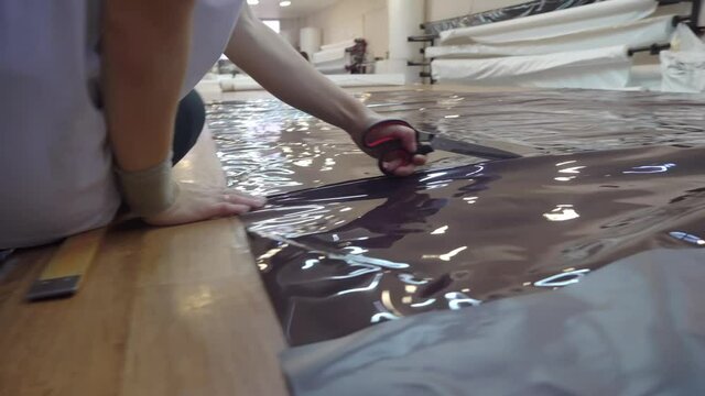 Women smooth and fold PVC film in the workshop for the production of stretch ceilings