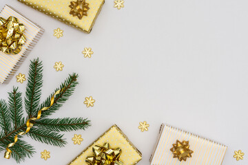 Festive background with gold decoration , green spruce branches and golden gift boxes with bow ,glittering snowflakes , flat lay, top view