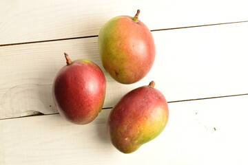 ripe mangoes, close-up, on a white wooden table.