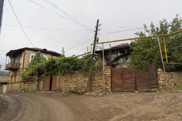 Street with big metal door and balcony house with disorganized electric cables and yellow gas pipes in the city of Hadrut part of the Janapar Trail in Nagorno Karabakh in the Republic of Artsakh