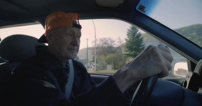 Close up, elderly man with backwards hat drivers car