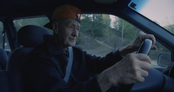 Elderly man with hat drives car, close up