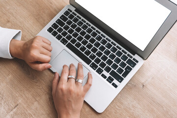 Blank laptop screen. A woman works behind a empty laptop at a desk.