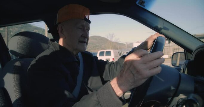Close up, old man with backwards hat drives car