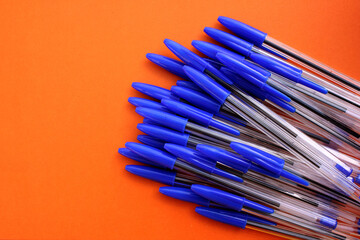 Fototapeta premium Ballpoint pens for writing on brown background. View from above. The case handles white, caps blue. Handles are located in the bottom right corner. Education. Schooling. For work. Flatlay. Copy spase.