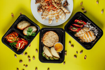 Healthy lunch at the workplace. Pick up food in black containers with Cutlery on a yellow background