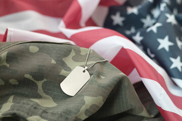 Silvery military beads with dog tag on United States fabric flag and camouflage uniform