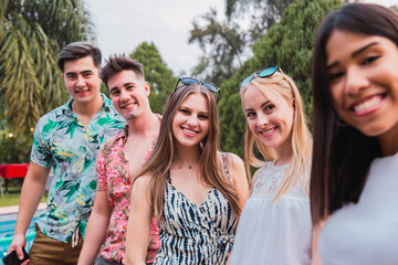 Portrait of millennial friends in an outdoor afternoon - Group of multiracial friends at a pool party.