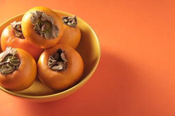 Orange persimmon on a yellow plate