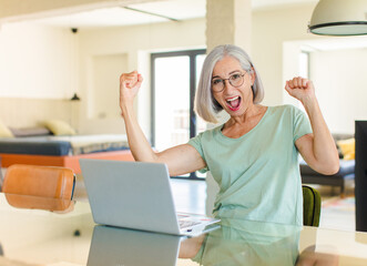 middle age woman shouting triumphantly, looking like excited, happy and surprised winner, celebrating