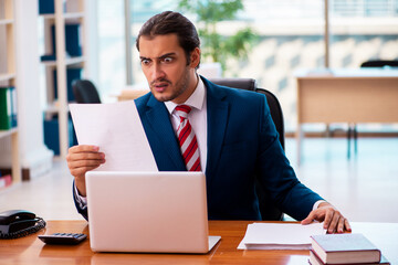 Fototapeta premium Young handsome employee working in the office