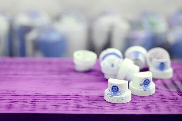 The soiled blue nozzles from the paint sprayer lies on a purple plank on a background of a many...