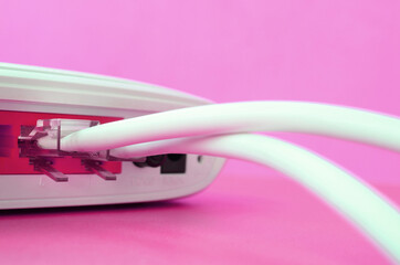 The Internet cable plugs are connected to the Internet router, which lies on a bright pink...