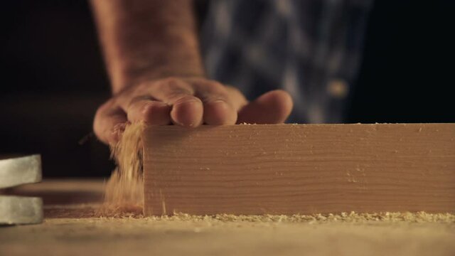 Man cleaning wooden shavings off the block