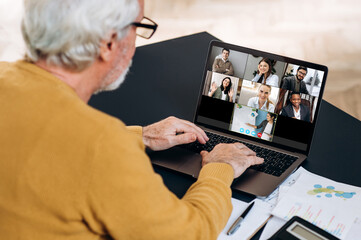 Video call communication. Elderly caucasian man is using a laptop for distant online studying, he...