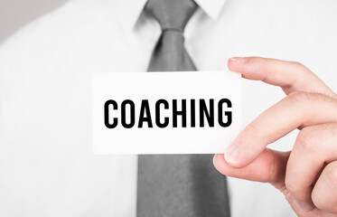 Businessman holding a card with text Coaching,business concept