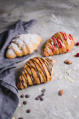 three fresh croissants on wooden board and cloth napkin