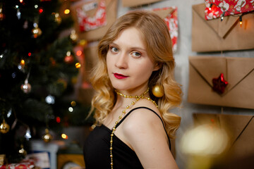 girl in a black dress against the background of a decorated Christmas tree