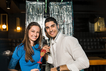 Portrait of happy young couple posing together at nightclub