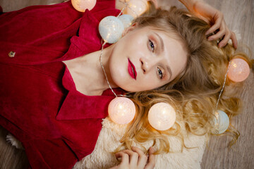 Close portrait of a cute lady with Christmas lights, looking at the camera