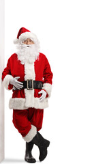 Full length portrait of santa claus leaning on a wall