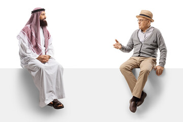 Saudi arab man in a thobe sitting on a blank panel with an elderly man and having a conversation