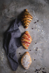three fresh croissants on wooden board and cloth napkin