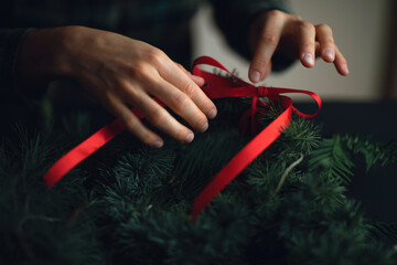 Creating Christmas wreath with pine tree and red ribbon. Ideas for christmas decoriation. Christmas background.