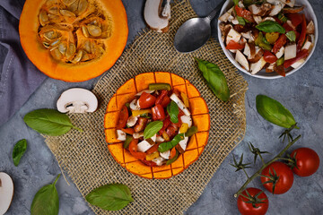 Top view of vegan baked Red kuri squash vegetable filled with bell pepper, tomatoes and mushrooms surrounded by ingredients