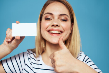 Woman with a business card in her hands a striped T-shirt blue background Copy Space