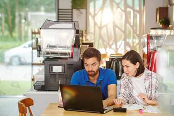 Small coffeeshop owners working on laptop and discussing ideas how to develop business in pandemic