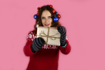 A beautiful girl decorated with Christmas toys holds a new year's gift in her hands