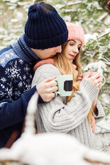 beautiful couple with hot tea in cups in forest