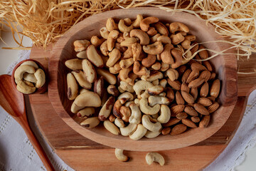 variety of nuts  in a wooden bowl and in two wooden cups with straw background. Main nuts of Brazilian cuisine.