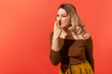 This is lie! Portrait of angry woman with blonde hair touching nose, showing liar gesture,...