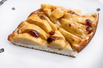 Apfeltarte mit Rosinen auf einem weißem Porzellanteller mit einem Art Deco Muster