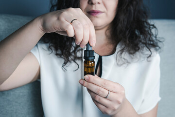 Close-up of females hand holding bottle with cbd oil drops