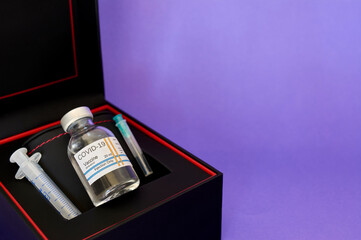COVID-19 coronavirus vaccine, protected in a gift box, black, for use, on purple background