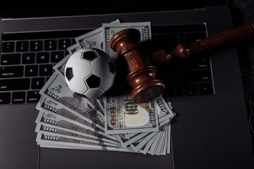 Soccer ball and wooden gavel on laptop's keyboard. Corruption in sports or betting concept.