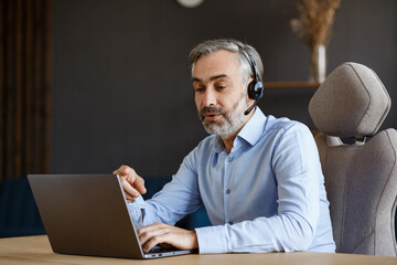 Online education, remote working, home education. Portrait of grey-haired senior handsome man teaching online. Online meeting, video call, video conference, courses online.