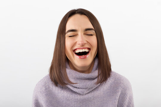 Happy cheerful young woman wearing her brunet hair rejoicing at positive news or birthday gift, looking at camera with joyful and charming smile. Student girl relaxing indoors after college
