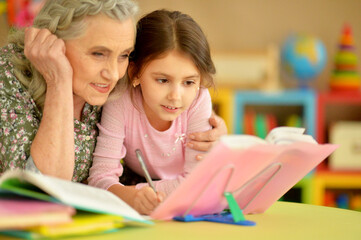 Grandmother with cute little girl doing homework