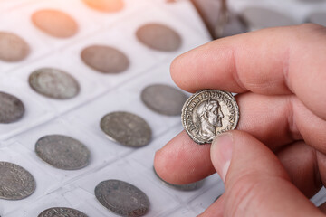 Numismatics. Old collectible coins made of silver on a wooden table. A collector holds an old...