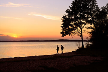 Fototapeta premium Retired people walking on the beautiful morning beach during sunrise