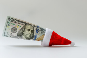 A hundred-dollar bill with the image of President Franklin is inserted in the Santa Claus hat. Free space for copying.